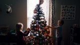 Kinder dekorieren einen festlich geschmückten Weihnachtsbaum